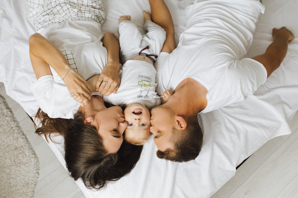 Familia descansando con su bebé en la cama
