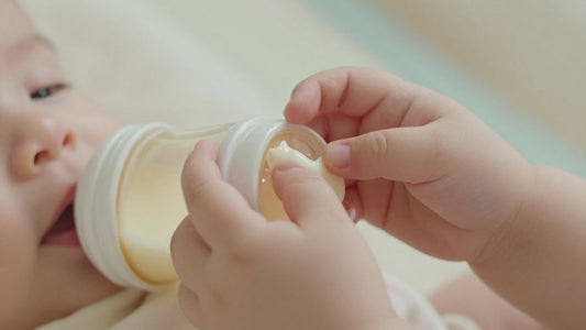 Bebé sosteniendo un biberón de leche de fórmula.