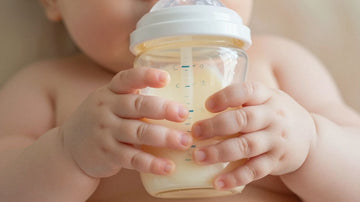Bebé con biberón de leche sin lactosa.