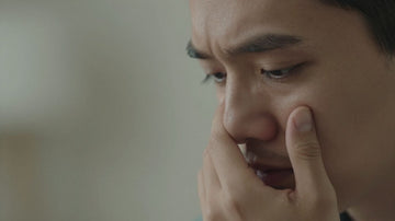 Persona tocando su sien con preocupación.