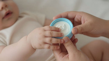 Manos de bebé sosteniendo un envase de leche de fórmula.