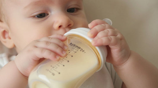 Manos de bebé sosteniendo un biberón de leche de fórmula.