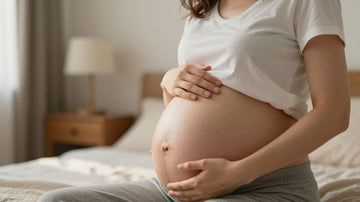 Mujer embarazada tocando su vientre con una sonrisa.