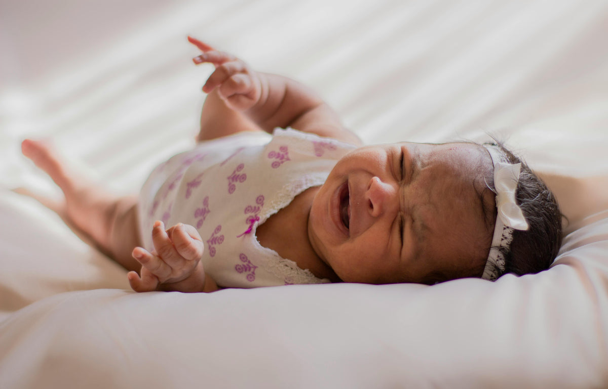 Bebé llorando tumbado en la cama